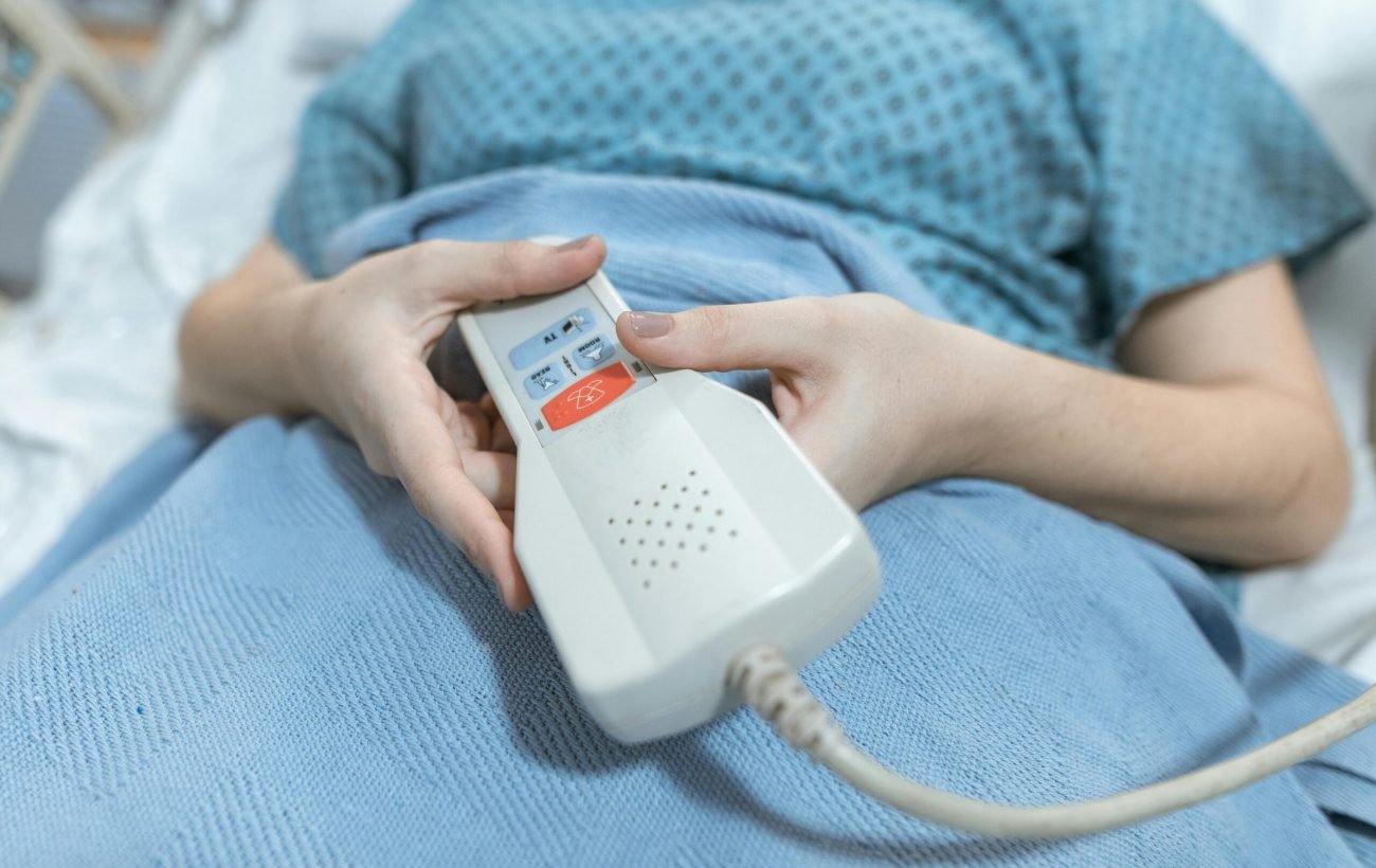 Close-up of a patient's hands holding a remote control in a hospital bed, showing care and medical settings.